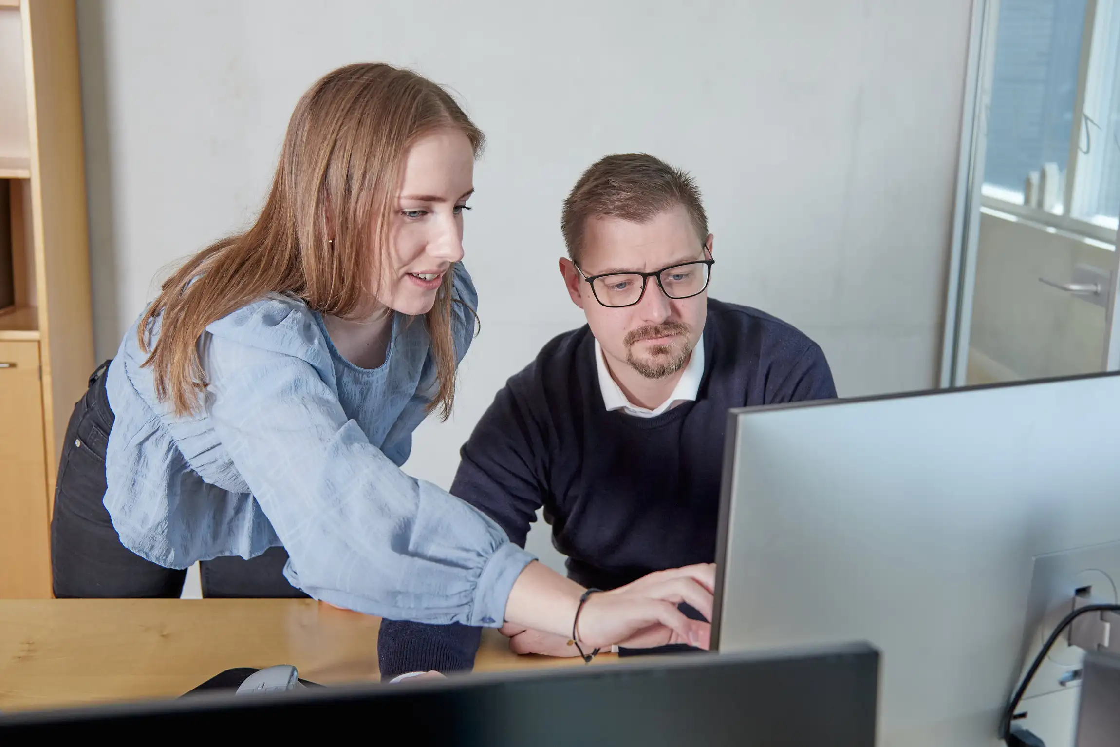 Kontormedarbejdere arbejder sammen ved en computer